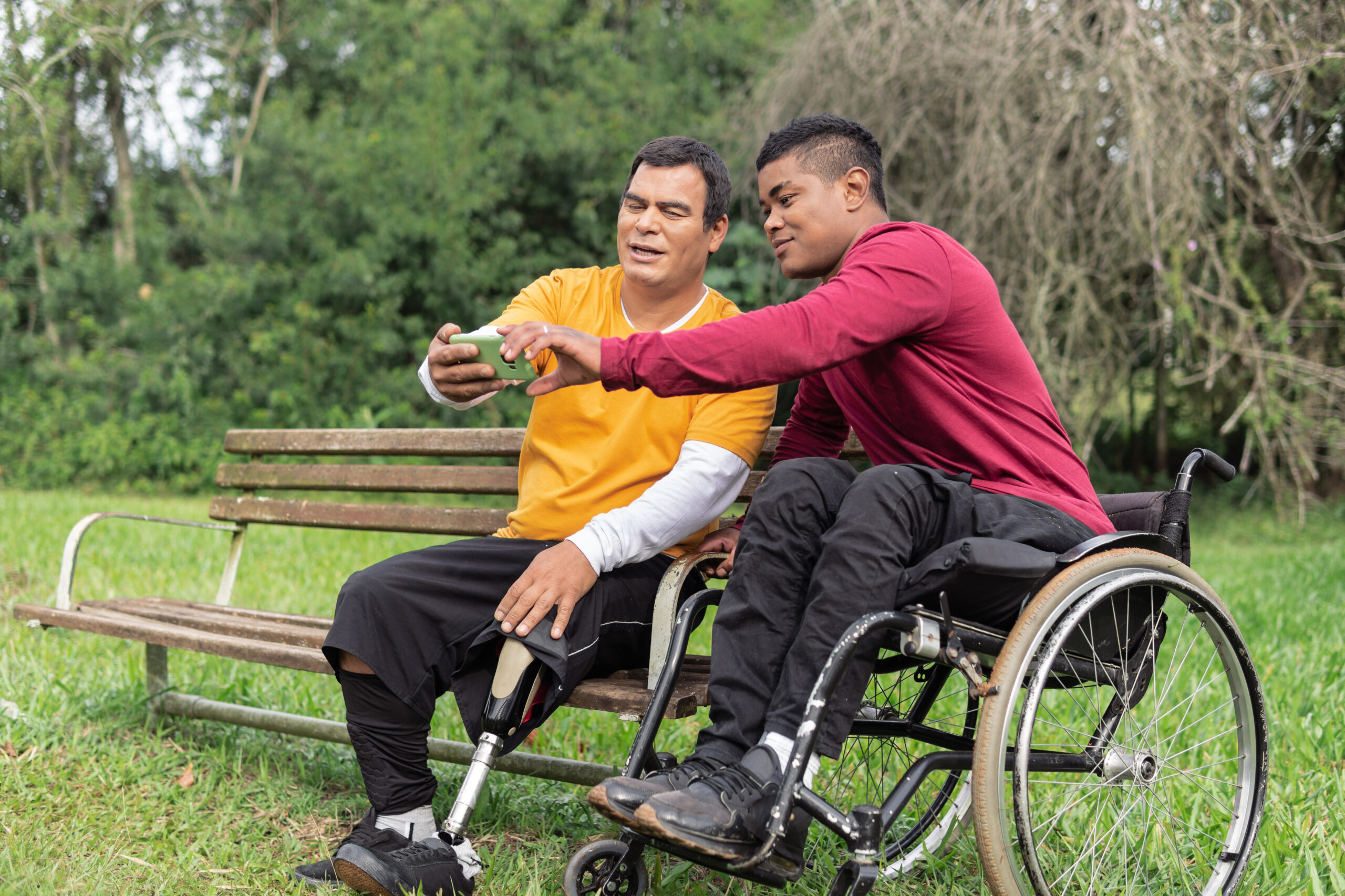 person in wheelchair and friend looking at cell phone screen... person in wheelchair and friend looking at cell phone screen...